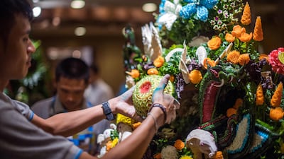 A Thai man helps put together an elaborate decoration with carved fruits and vegetables during a fruit and vegetable carving competition in Bangkok. Robert Schmidt / AFP