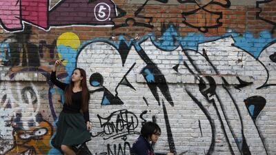 A woman poses for her self-portrait with her mobile phone while another works on a painting in front of a graffiti during the 2013 Beijing 798 Art Festival at the 798 Art Zone in Beijing. The art zone, originally an unused factory, was transformed into a landmark of contemporary art in Beijing in the 1990s. The annual art festival goes on till October 20. Kim Kyung-Hoon/Reuters