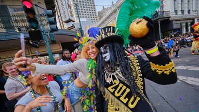 A member of the crowd poses for a photo with a member of the Krewe of Zulu. EPA