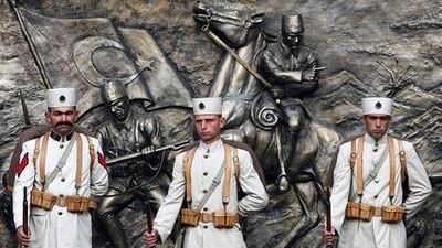 Soldiers dressed in uniforms of the Turkish War of Independence stand in front of a tribute to Mustafa Kemal Ataturk.