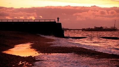 A woman takes a photo of Brighton Palace Pier and the sunrise in Brighton, Britain. Reuters