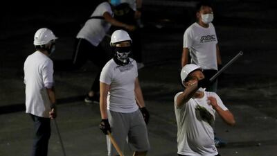 Men in white shirts with poles are seen in Yuen Long. Reuters