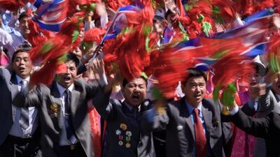 Participants wave flowers as they march past a balcony from where North Korea's leader Kim Jong Un was watching, during a mass rally on Kim Il Sung square in Pyongyang. AFP