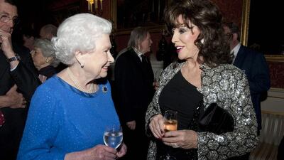 Queen Elizabeth II talks to the actress Joan Collins, who was made a dame at the Queen's New Year honours. David Crump / Getty Images