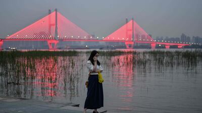 A woman wearing a face mask as a preventive measure against the coronavirus talks on her phone next to the Yangtze River in Wuhan, in China’s central Hubei province. AFP