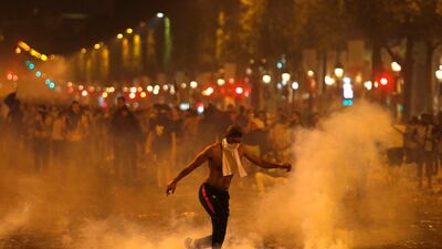 A man kicks a tear gas canister fired by police during clashes on the Champs Elysees as French soccer fans celebrated winning the World Cup. Thibault Camus / AP Photo