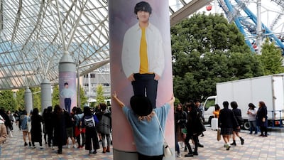 A woman hugs a wall photo of a member of South Korean boy band BTS outside Tokyo Dome. Kim Kyung-Hoon / Reuters