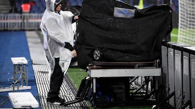 A journalist covers his equipment during heavy rain prior to the French L1 football match between Paris Saint-Germain (PSG) and Lyon (OL) at the Parc des Princes stadium in Paris. AFP