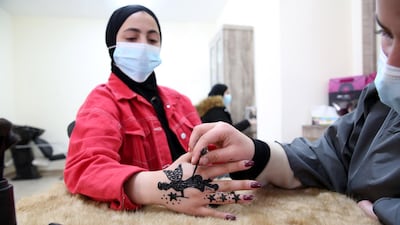 A girl watches closely as Palestinian henna tattoo artist Samah Sidr draws a tattoo on her hand, at her shop in the West Bank city of Hebron. EPA