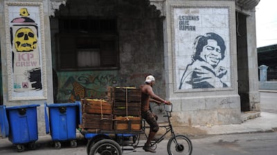 A Cuban passes on his bycicle by a graffiti of street art in Havana, on July 12, 2017. / AFP PHOTO / YAMIL LAGE