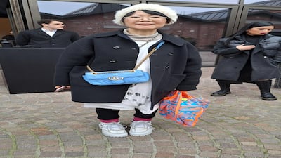 Low-key style with a beanie and bold graphic bag, outside the Gucci show