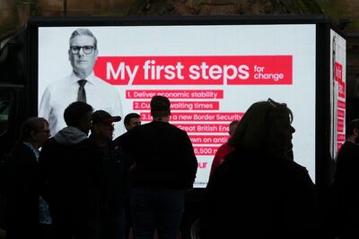 Labour party supporters stand next to a digital billboard featuring Keir Starmer's six election pledges, in Leigh last week. Getty Images