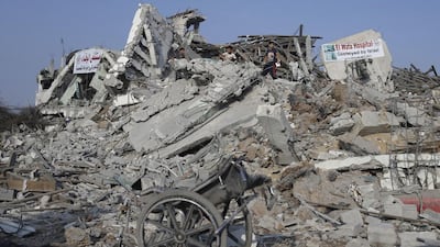 Palestinians stand atop the ruins of the headquarters of El Wafa rehabilitation hospital. Ibraheem Abu Mustafa / Reuters