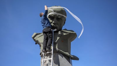 An activist bandages shrapnel holes on the monument of Ukrainian poet Taras Shevchenko in Borodyanka after Russian forces withdrew from the town north-west of Kyiv. AFP