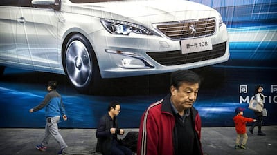 People walk past an advertisement for a foreign auto maker on a wall on October 27, 2014 in Beijing, China. Economic data showed that the country's growth dropped to a five year low and is slowing due to a decrease in exports and property development in recent months, reports say. Kevin Frayer / Getty Images