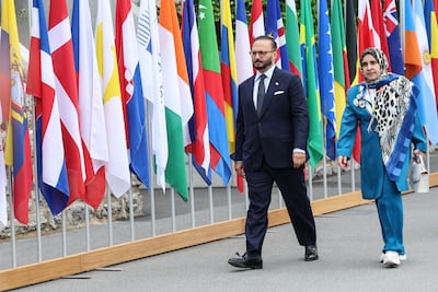 Diplomatic advisor to the United Arab Emirates President Anwar Gargash (L) walks in front of the flags during the Summit on Peace in Ukraine. Getty