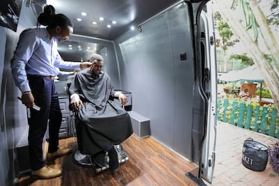 Kenyan barber Barkat Manji (L) gives a haircut to a client inside his recently acquired Mercedes-Benz Sprinter van that he converted into a mobile barbershop, outside his barbershop branch in Nairobi, Kenya, 05 October. EPA
