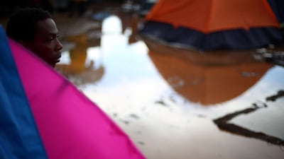 A migrant looks out from his tent after heavy rainfall. Reuters