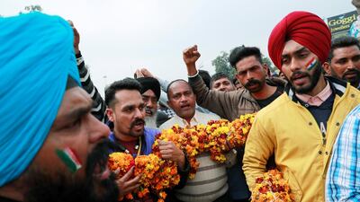 People hold a garland as they chant before the arrival of the Indian Air Force pilot, who was captured by Pakistan. Reuters