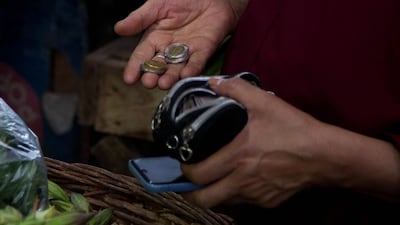 A customer selects Egyptian currency coins at the Al-Manhal market in the Nasr city district of Cairo. Bloomberg