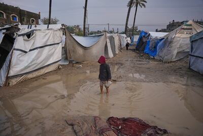 A boy crosses a muddy puddle in a tent camp in Deir Al Balah, in central Gaza, following heavy rain. AP
