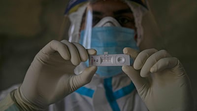 A health worker displays a test kit showing a positive result for Covid-19 in Gauhati, India. AP Photo