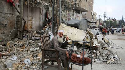 An injured man sits by the ruins of a house in Rafah, southern Gaza, following an Israeli strike. Reuters