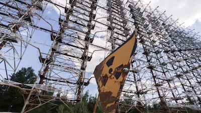 A rusty radioactivity warning sign sits beneath the inter-ballistic early warning radar system, known as Duga Radar, in the Chernobyl exclusion zone. Bloomberg