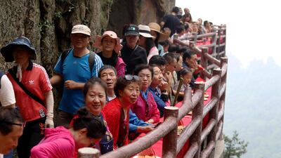 Tourists squeeze by other guests to reach their seats on the cliff edge. AFP