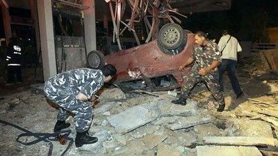 Lebanese policemen inspect a damaged car at a destroyed gas station in Beirut Lebanon. AP Photo