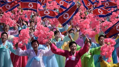 Participants wave flowers as they march past a balcony from where North Korea's leader Kim Jong Un was watching, during a mass rally on Kim Il Sung square in Pyongyang. AFP