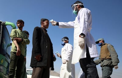 Health workers measure the temperature of Afghan passengers in an effort to prevent the spread of the coronavirus in Kabul. AP