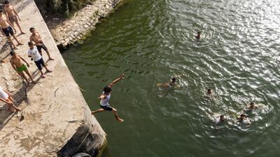 Egyptian youths dive into the water at the entrance of a canal near the Nile river delta barrages in Qanater al-Khayreya, north of Cairo, during the holiday of Sham al-Nessim. AFP