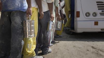Labourers line up to board their bus. From June 15 until September 15, labourers have a right to an extended midday break due to the extreme heat in the region. Silvia Razgova / The National