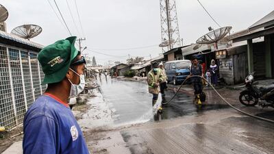 Men washing away the fallen ash after nearby Mount Sinabung volcano erupted, in the town Karo North Sumatra. Ivan Damanik / AFP