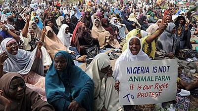 Muslim women holding placards pray during Jumat service in a protest against the increase in petrol prices by the government.