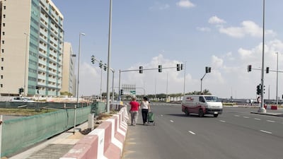 Residents of Al Bandar and Al Muneera walk along the road to cross from one community to the other. Reem Mohammed / The National