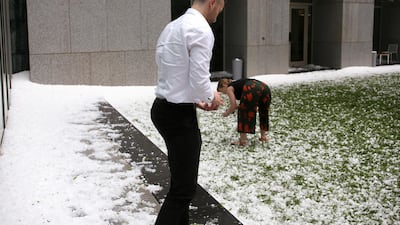 A man and woman collect golfball-sized hail on the grounds of Parliament House in Canberra, Australia, after a storm battered the Australian capital. AP Photo