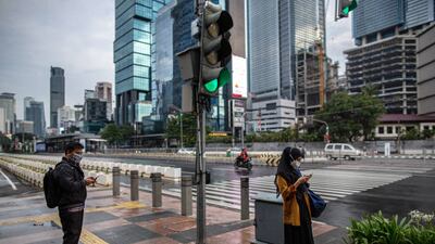 People wait to cross a road in Jakarta. Lockdowns and other measures to slow the spread of the coronavirus have weighed on Indonesia's economic activity, with the PMI for August showing a contraction in the country's manufacturing sector. Getty Images