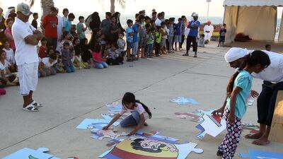 Children assemble large puzzles at the Al Gharbia Watersports Festival.