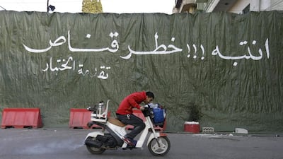 A coffee street vendor passes on his scooter in front a green tarp hung to provide cover from snipers, during clashes between supporters and opponents of Syrian President Bashar Assad in the northern port city of Tripoli, Lebanon. The Arabic words on the tarp read:’Be aware!!! Danger sniper.’ Hussein Malla / AP Photo