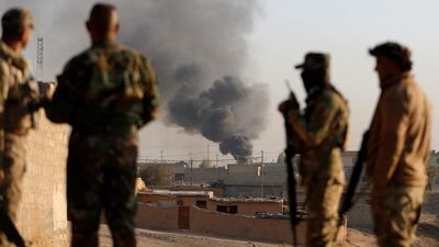 Iraqi soldiers look as smoke rises over the village of Al-Qasar during fighting between Iraqi soldiers and ISIL fighters.