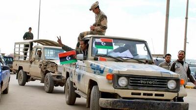 Security forces who have joined the uprising carry the flag of Libya's monarchy, as they drive through Benghazi, Libya.