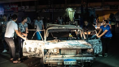 People surrounding a burned car after the explosion in downtown Cairo. AFP