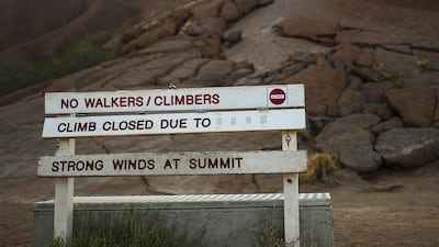 The sign at the bottom of the climb area indicates the climb is closed due to 'strong winds at summit at Uluru. EPA