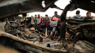 Palestinians gather around the remains of a vehicle that was destroyed. Reuters