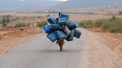 A man on a motorcycle in Oujda, near Morocco’s Mediterranean coast, carries empty barrels into Algeria to fill with oil and smuggle back into Morocco. Fadel Senna / AFP