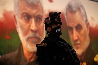 A member of Iraq's Hashed Al Shaabi on guard in front of a banner depicting assassinated Iraqi commander Abu Mahdi Al Muhandis, left, and Iranian Islamic Revolutionary Guard Corps commander Gen Qassem Suleimani, near Baghdad's International Airport on January 2, 2023 during a ceremony marking the third anniversary of their deaths. AFP