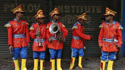 Local band members wait for a bus to take them to a wedding venue where they are booked to perform.