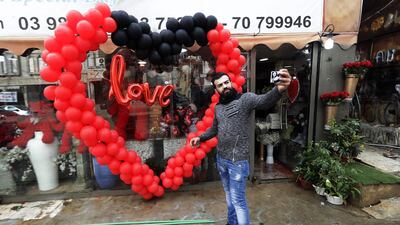A man takes a selfie in front of a shop decorated for Valentine's Day in Beirut / AFP
